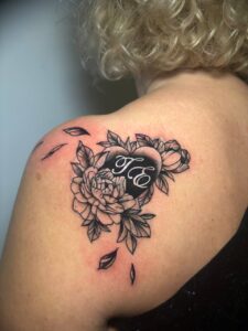 Tatuaggio copertura fiori neri e foglie sulla spalla Umbria Acca Elena Ink