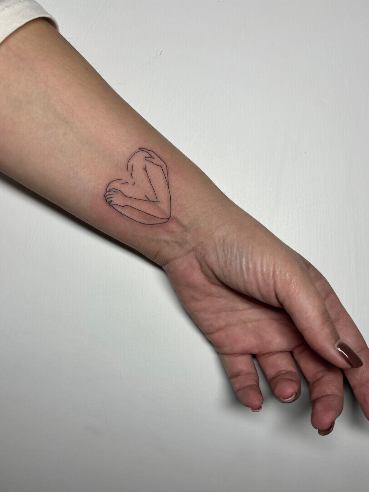 Tatuaggio fine line cuore stilizzato sul polso Umbria Acca Elena Ink